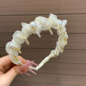 Detail view of cream wavy pleated fabric headband with large pearls and inner grip teeth