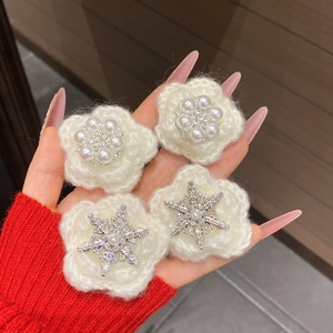 Close-up of four white knitted snowflake hair clips with pearls and rhinestones