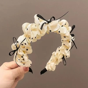 Detail view of beige polka dot headband featuring ruffled silk fabric and small black bows