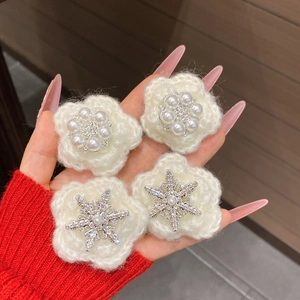 Close-up of four handmade white crochet flower clips with pearl and snowflake crystal centers