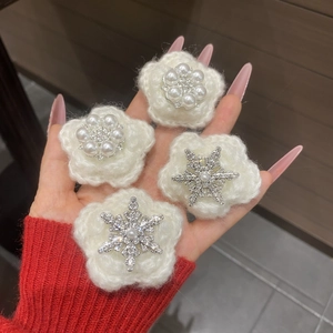 Close-up of four white plush flower hair clips with pearl centers and snowflake rhinestones