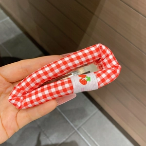 Détail de la pince à cheveux à carreaux vichy rouges et blancs avec broderie cerise