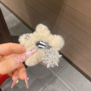 Detail view of cream plush star hair clip featuring snowflake rhinestones and soft fur