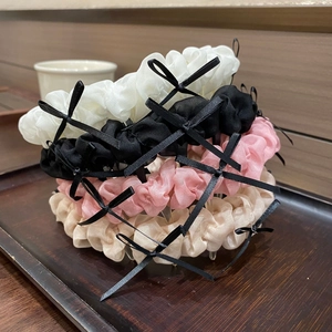 Détail de serre-têtes en tissu ondulé avec petits nœuds noirs et dents antidérapantes