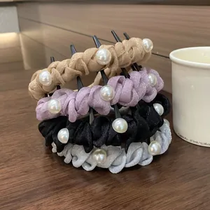 Close-up of pearl-studded fabric headbands in various colors on a wooden table