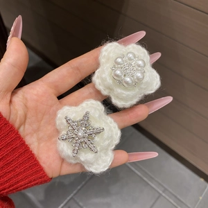 Close-up of handmade white knitted snowflake hair clips with pearl and rhinestone details