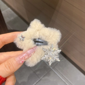 Detailed view of plush cream star hair clip with rhinestone snowflake and pearl center
