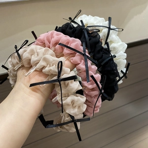 Détail de serre-têtes en tissu plissé de différentes couleurs avec nœuds noirs et dents