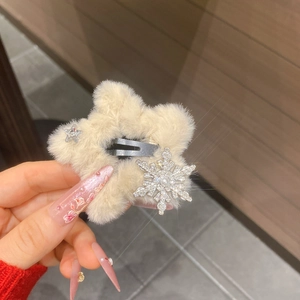 Close-up of a plush beige star hair clip featuring rhinestone snowflake decoration
