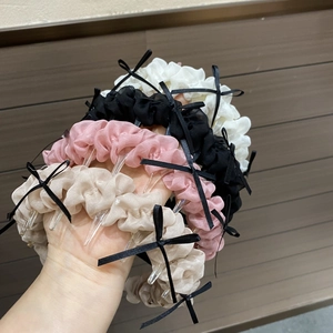 Détail des dents antidérapantes à l'intérieur d'un serre-tête en tissu plissé avec nœuds