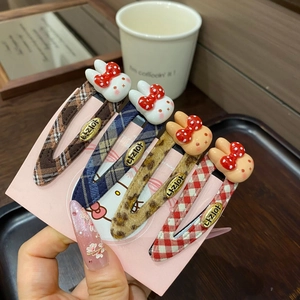 Detail of four plaid pattern BB hair clips with cute cartoon rabbits held by hand