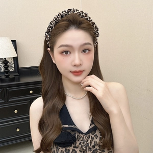 Close-up detail of leopard print fabric headband with pleated texture on model