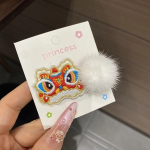 Detailed embroidery of a traditional Chinese lion head hair clip with a fluffy pompom