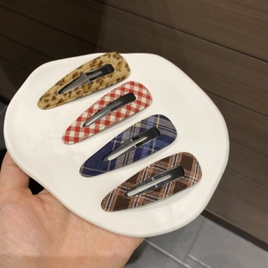 Detailed view of four teardrop hair clips featuring leopard and plaid fabric patterns