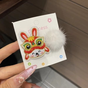 Close-up of traditional Chinese New Year lion rabbit embroidery hair clip with white pompom