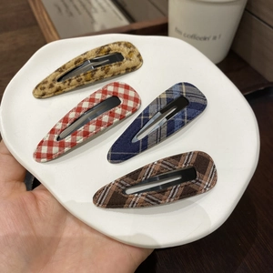 Set of 4 blue plaid and leopard fabric BB hair clips for women in a ceramic dish