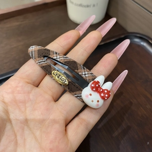 Close-up of a brown plaid BB hair clip featuring a cute 3D bunny and a golden logo tag