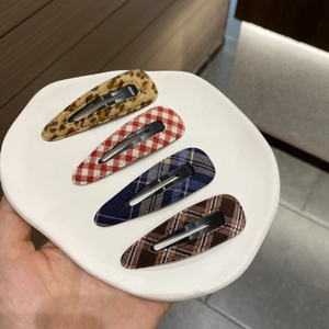 Detailed set of four plaid and leopard print fabric BB hair clips on a ceramic plate