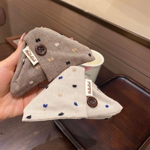 Détail d'une pince à cheveux triangulaire en tissu à pois avec bouton et tons chauds