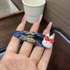 Detail of blue plaid fabric hair clip with a cute 3D resin rabbit and gold metal tag