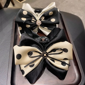 Detail of satin bow hair clips with polka dots and camellia flower accents on wood