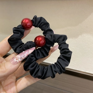 Close-up of black pleated elastic hair ties featuring glossy large deep red beads