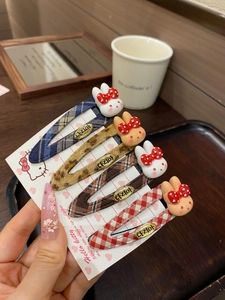 Close-up of four plaid snap hair clips with cute bunny charms and gold engraved plates