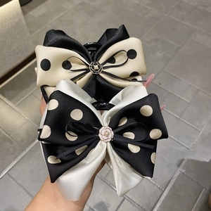 Detailed close-up of polka dot satin hair claws with pearl camellia metal accents
