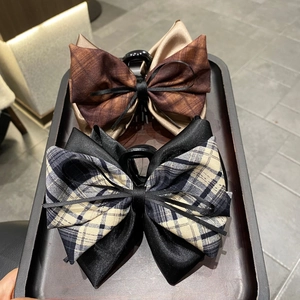 Close-up of elegant plaid and satin ribbon hair claws in brown and black styles