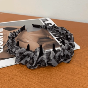 Detail of leopard print mesh headband with black spikes on a fashion magazine