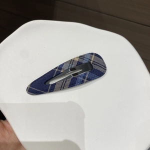 Detail of navy blue plaid fabric texture on a vintage oval BB hair clip for women