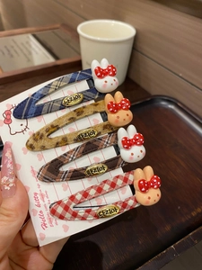 Detail of four plaid snap hair clips with bunny resin charms on a display card