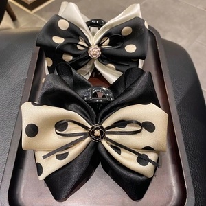 Elegant bow hair clips with polka dots and pearl camellia details on a wooden tray