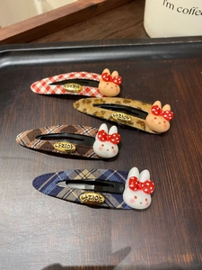 Close-up of four cute bunny BB hair clips with plaid patterns on a wooden tray