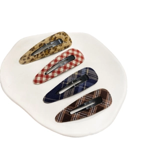 Set of four blue plaid and leopard print BB hair clips on a white ceramic plate