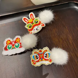 Detailed embroidery of rabbit, lion, and tiger clips with white pom poms on a wooden tray