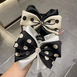 Detailed view of polka dot satin bow hair claw clips with camellia pearl center accents