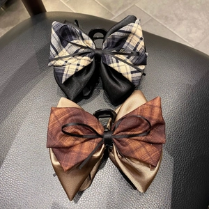 Detail view of plaid ribbon hair claw clips with black satin bow and sturdy plastic teeth