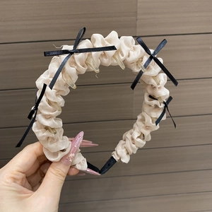 Détail du bandeau en satin plissé rose avec nœuds noirs et clips de maintien internes