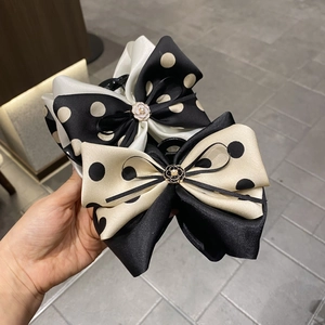 Detail of polka dot bow hair claw clip with camellia metal and pearl centerpiece