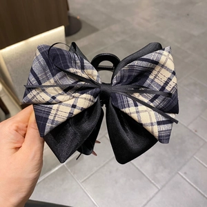 Detail of a large 13cm dark blue plaid bow hair claw clip with black satin ribbons
