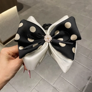 Detail of elegant black and white polka dot bow hair claw with camellia flower and pearl