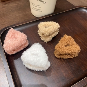 Dettaglio di quattro mollette in peluche rosa beige bianco e marrone su vassoio in legno