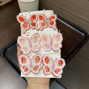 Détail de barrettes papillon brodées avec fil doré et perles nacrées pour petites filles