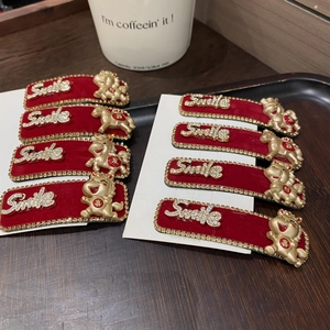 Detail von roten Samt-Haarspangen mit goldenem Sternzeichen Pferd und Glitzer Smile-Schrift