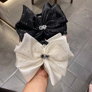 Détail de pinces à cheveux en satin avec nœuds et strass en cœur noirs et blancs