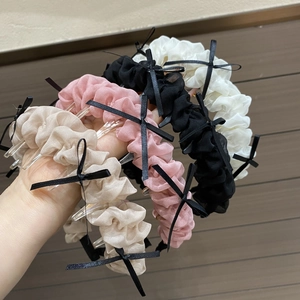 Détail de quatre serre-têtes en tissu plissé avec petits nœuds noirs en beige, rose et blanc