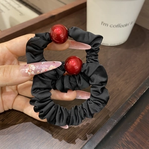 Close-up of black satin hair scrunchies with elegant red bead ornaments in a set of two