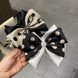 Detail view of satin bow hair claws with polka dots, camellia accents and pearls