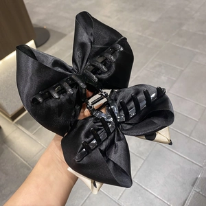 Detail view of large black satin bow hair claw clip with elegant polka dot lining detail